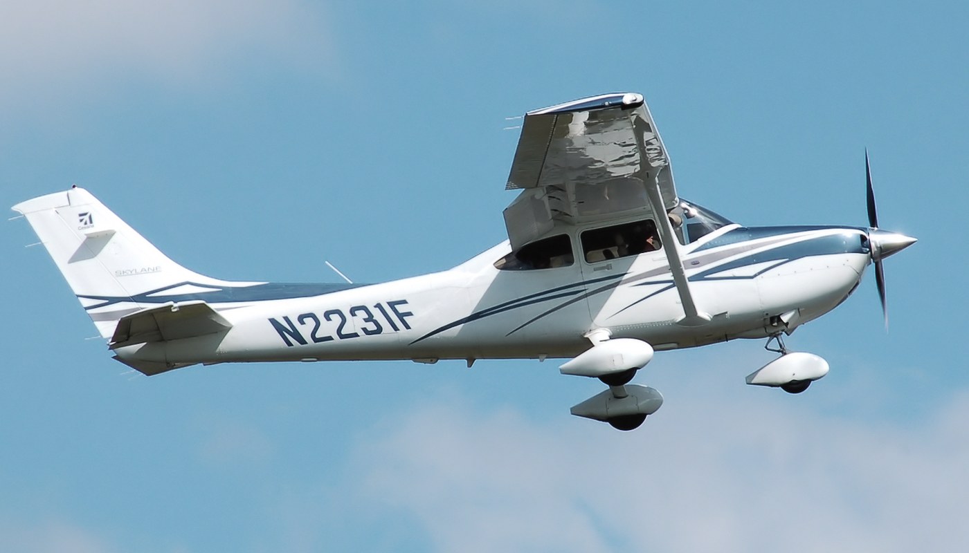 A Cessna 182T Skylane (N2231F) climbing out against a bright blue sky — the slightly bigger and more powerful sibling of the 172